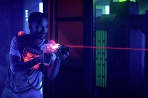 laser tag player holding gun shooting light in black light labyr